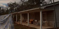 a house that has some chairs on the front porch and covered in a tarp