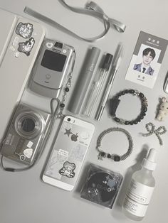 an assortment of personal items are laid out on a table with a camera, cell phone and other accessories