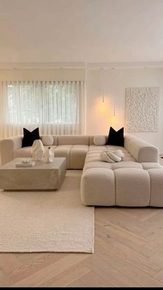 a living room with white furniture and wood flooring in front of a large window