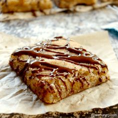 a piece of cake with chocolate drizzled on it sitting on wax paper