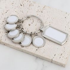 a set of four keychains sitting on top of a marble slab with blank tags