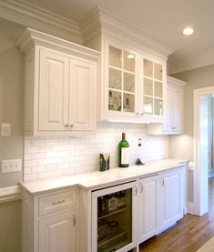 a kitchen with white cabinets and an oven in the center is shown, along with a wine cooler