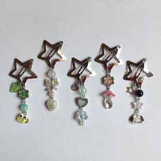 six different colored charms hanging from the side of a white surface, each with a star shaped charm attached to it