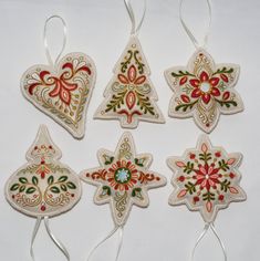 four ornaments are hanging from strings on a white surface