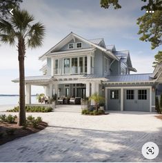 a large white house sitting on top of a sandy beach next to the ocean with palm trees