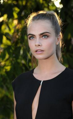 a woman with blonde hair and blue eyes wearing a black dress is looking at the camera