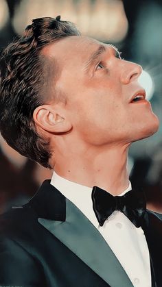 a man in a tuxedo looking up to the sky with his eyes closed