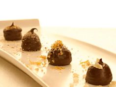 four pieces of chocolate on a white plate with sprinkles and orange zest