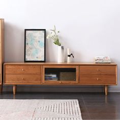 a living room with a wooden entertainment center and white rug on the floor next to it