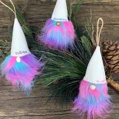 three party hats with pink, blue and purple feathers on them next to pine cones