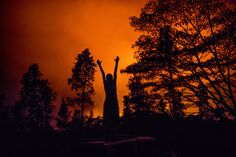 a person standing in the dark with their arms up and hands raised above their head