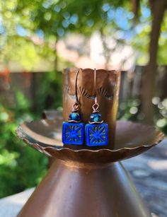 The centerpiece for these stunning boho earrings is a cobalt blue tile bead with a gorgeous starburst.  Another petite pair of earrings! Simply gorgeous Czech glass! Love the look! These unique beauties are just under two inches in length, including the copper hooks.  The Czech glass square bead is accented with a complimentary Rondelle bead and wavy copper disc.  These square starburst beads are some of my favorite beads because of the richness of the color and the design.  One of a kind. Lightweight! Petite. Handmade. Smoke free artist studio. Artisan Blue Earrings, Artisan Blue Nickel-free Earrings, Artisan Blue Drop Earrings, Artisan Blue Earrings For Festival, Blue Earrings With Ear Wire For Festival, Bohemian Blue Nickel-free Earrings, Nickel-free Blue Earrings For Festival, Blue Drop Earrings For Festival, Adjustable Blue Earrings For Festival