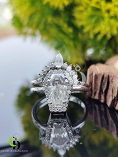 a diamond ring sitting on top of a glass table next to a tree stump and yellow flowers