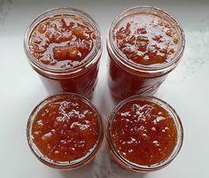 three jars filled with jam sitting on top of a counter