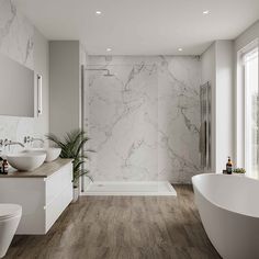 a bathroom with marble walls and flooring, two sinks, a tub, and a toilet