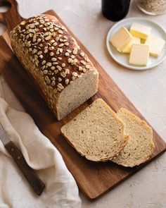 a loaf of bread sitting on top of a cutting board next to slices of bread