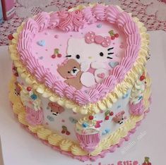 a heart shaped cake with hello kitty decorations on it's sides and pink frosting