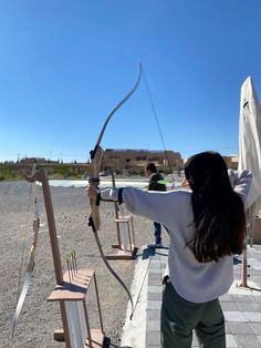 a woman is aiming an arrow at something