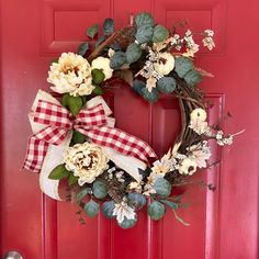 a red door with a wreath on it and flowers hanging from the front door handle