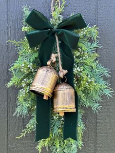 an evergreen wreath with two bells hanging from it