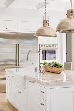 a kitchen with two pendant lights over the sink and an island in front of it