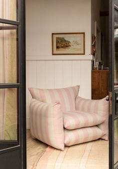 a pink and white striped chair sitting on top of a floor next to a doorway