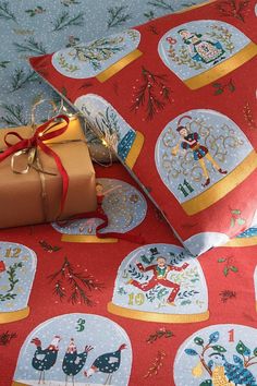 a present wrapped in brown paper on top of a red table cloth with christmas designs