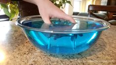 a hand reaching into a bowl with blue liquid in it