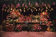 a flower shop with lots of flowers and lights hanging from the ceiling over it's tables