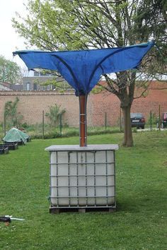 a blue umbrella sitting on top of a white box in the middle of a field