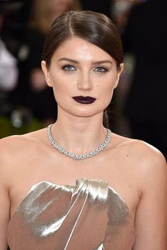 a woman with dark lipstick wearing a silver dress and diamond choker on her neck