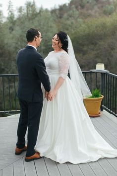 a bride and groom standing on a deck looking into each other's eyes as they hold hands