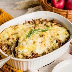 a casserole dish with meat and cheese in it on a table next to bread