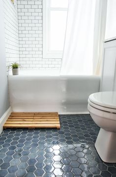 a white toilet sitting next to a bath tub in a bathroom with blue tile on the floor