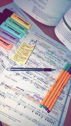 several pencils and notes on top of a table with music sheets in the background