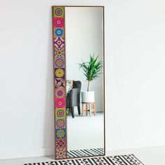 a mirror sitting on top of a white floor next to a potted green plant