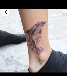 a woman's foot with a dolphin tattoo on it