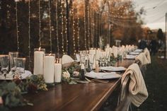 a long table is set with candles, plates and napkins for an outdoor dinner