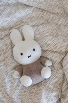 a stuffed animal laying on top of a bed next to a white and brown blanket