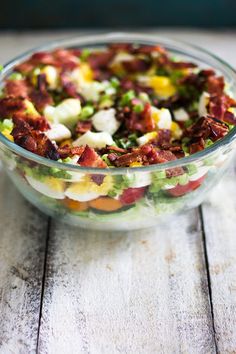 a glass bowl filled with salad on top of a wooden table