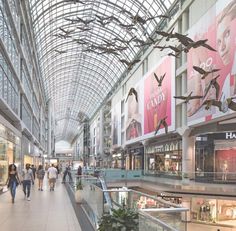 people are walking through the mall with their shopping bags in hand and birds flying overhead