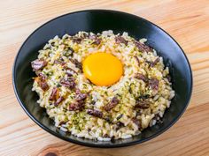 an egg on top of rice in a black bowl