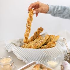 a person reaching for some bread sticks in a bowl