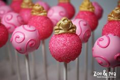 pink cake pops with gold crown decorations on top are ready to be served for guests