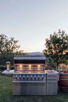 an outdoor bbq grill with several lights on it and two barrels next to it