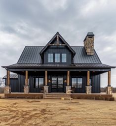 a large black house sitting on top of a dry grass field