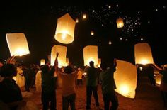 people releasing lanterns into the sky at night