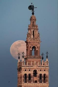 a tall tower with a clock on it's side and a full moon in the background