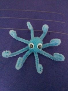 an octopus made out of yarn sitting on top of a purple surface with eyes drawn on it