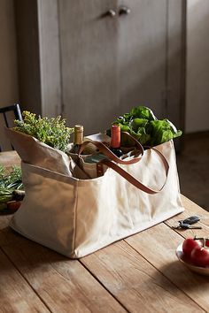 an open tote bag sitting on top of a wooden table next to tomatoes and lettuce